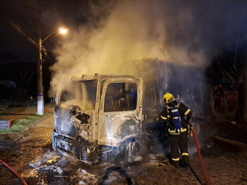 Foto mostra bombeiro apagando fogo de caminhão de lixo incendiado