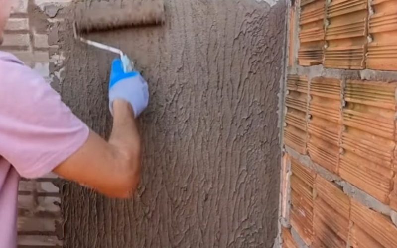 Frame de vídeo em que pedreiro ensina a fazer textura de parede