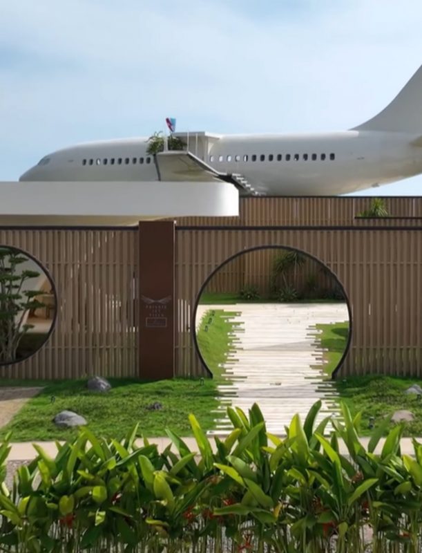 Avião que foi transformado em casa ao fundo, com hall de entrada da casa com plantas de primeiro plano