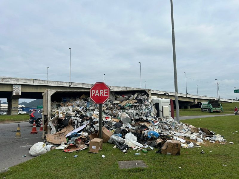 Imagem mostra caminhão tombado no trevo de Itajaí com lixo espalhado pela região