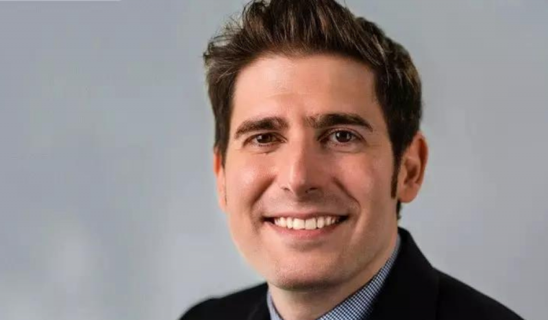 Eduardo Saverin, o brasileiro mais rico do mundo - Foto mostra homem branco com fundo de pele rosado sorrindo olhando direto para a câmera. Ele tem olhos castanhos escuros e cabelos castanhos claros.