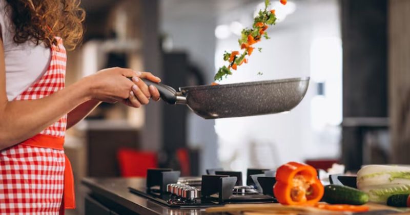 Pessoa segurando uma panela cinza e jogando comida para cima