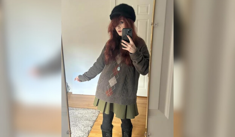 Foto mostra jovem ruiva usando boina e casacos tirando foto na frente do espelho