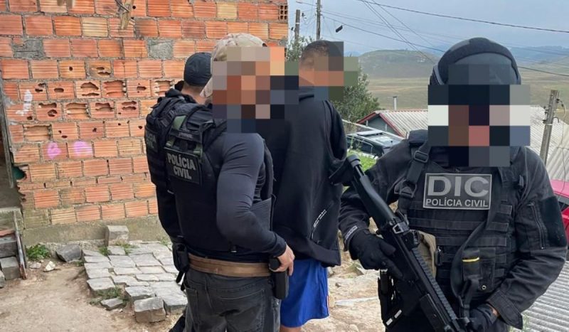 Foto mostra policiais armados prenderem homem suspeito de ter entregue as armas usadas na morte