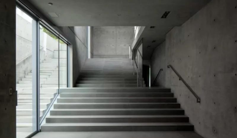 Foto mostra dois lances de escadaria, com paredes cinzas e concreto