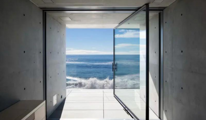 Mansão do Kanye West - Foto mostra vista de dentro de paredes de vidro e no fundo o mar e céu azuis