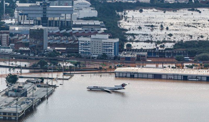 Voos do aeroporto foram cancelados - Foto mostra avião no meio de inundação em pátio de aeroporto