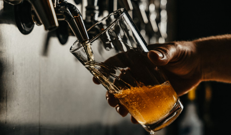 mão segurando um cop de chopp enquanto enche na chopeira em uma boate 