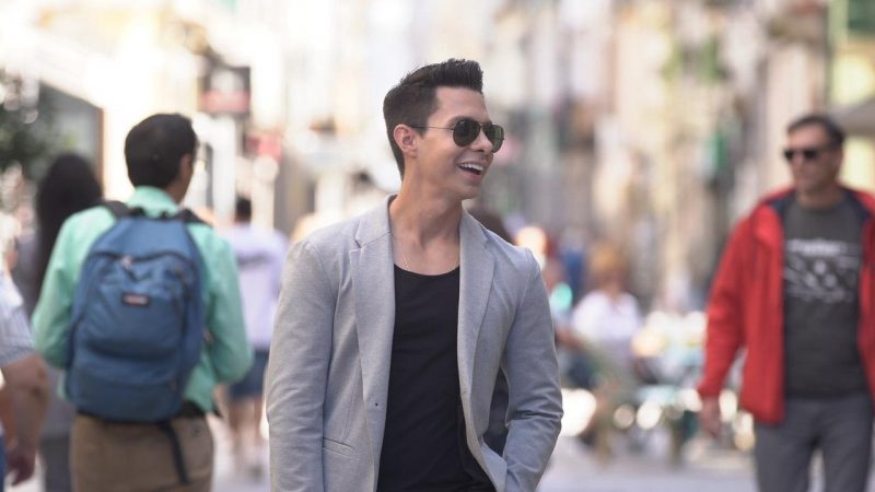 Patriolino Ribeiro aparece sorrindo de óculos escuros entre as pessoas na rua