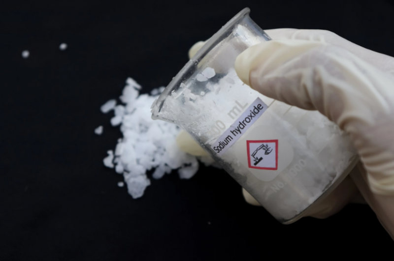 Imagem de uma soda cáustica na mão de uma pessoa