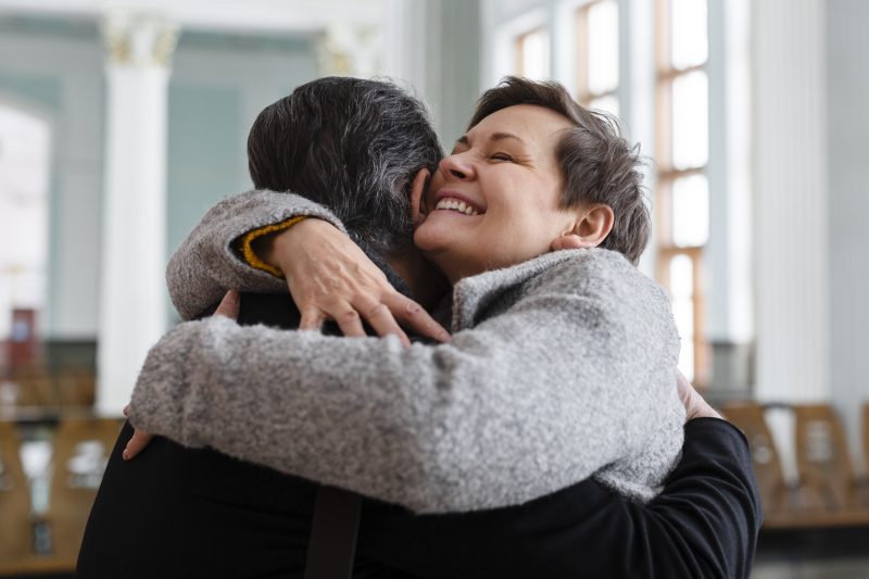 na imagem aparecem duas pessoas com abraços apertados no fim de ano e se cumprimentando