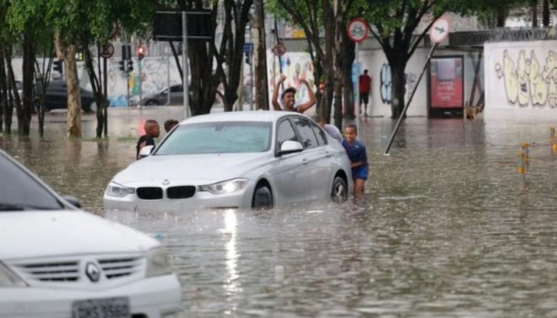 Enchentes e pessoas ajudando carro debaixo da água