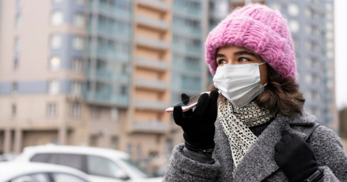 Mulher falando no celular usando touca e cachecol no frio