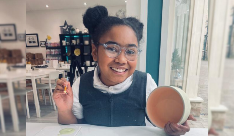 Menina com tumor que tomava paracetamol - Foto mostra menina negra com penteado de coque sorrindo segurando itens de pintura nas mãos