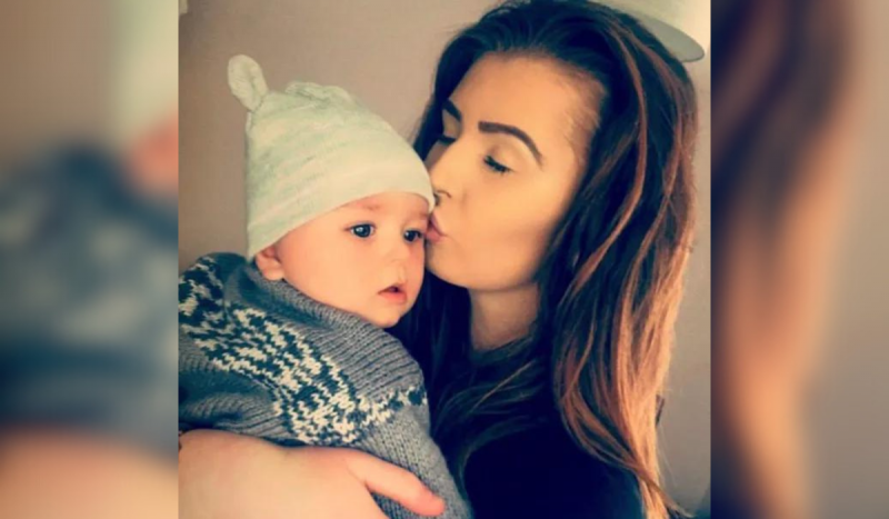 Mulher branca beijando em cabeça de bebê usando touca azul listrada