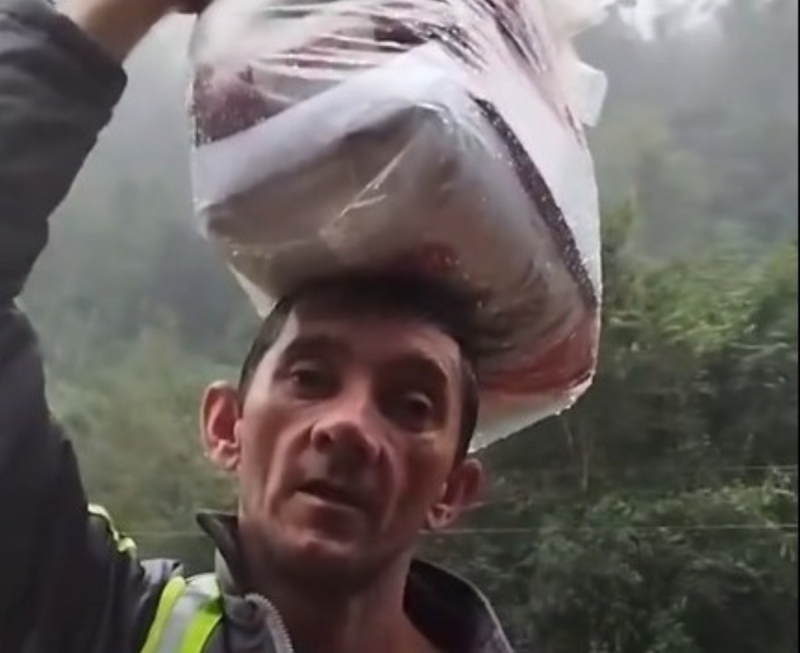 Pai carrega mantimentos na cabe&ccedil;a, enquanto produtos de limpeza s&atilde;o levados na m&atilde;o – Foto: Altair Pape/Reprodu&ccedil;&atilde;o/ND