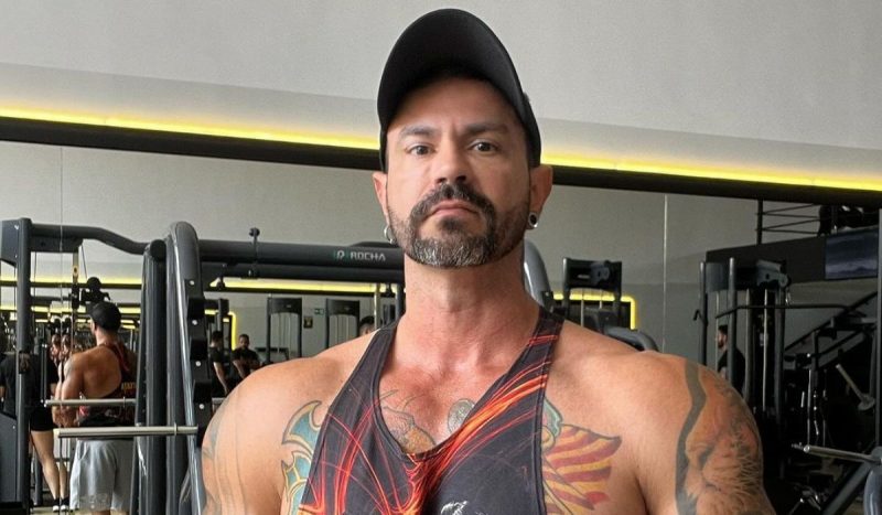 personal trainer aparece olhando para foto sério usando uma regata e um boné