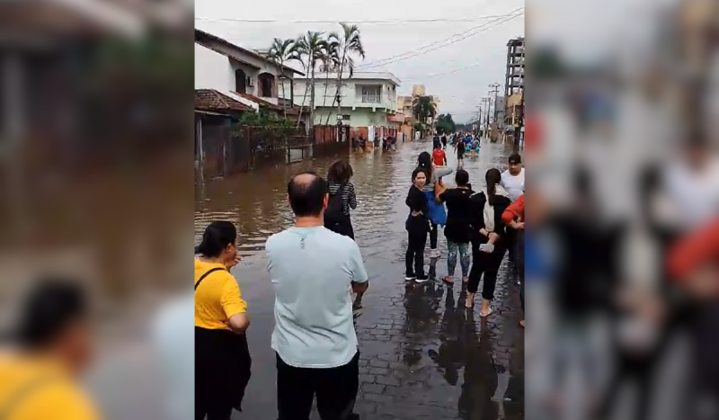Pessoas olhando água de enchente subir em rua