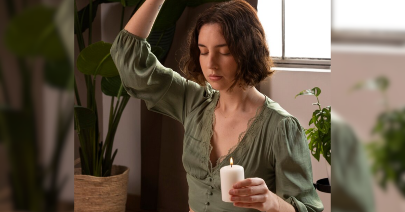 Mulher com vela na mão se preparando para ritual com ervas