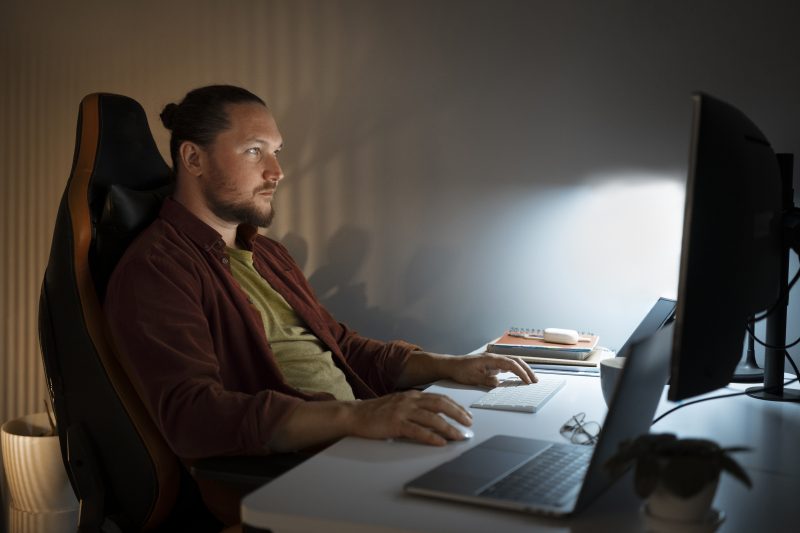 Homem sentado em frente a um computador