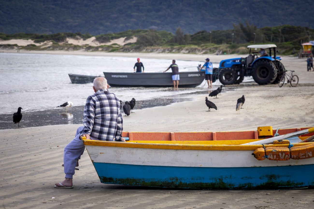 Pescadores Imagem de um senhor perto de um barco de pesca, para fazer alusão ao valor máximo de pesca da tainha permitido