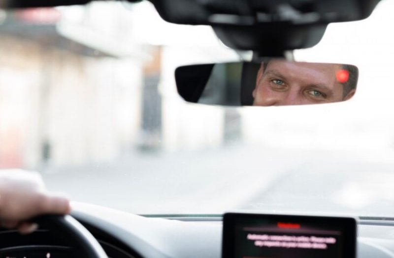 na imagem, motorista se olha no espelho e percebe que está sendo filmado em um dos carros por dispositivo 