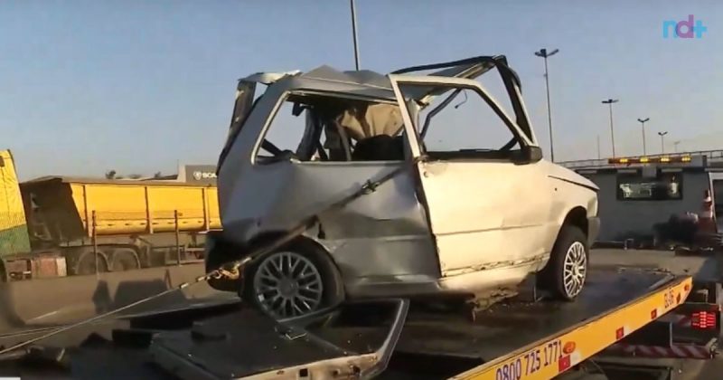 Imagem mostra veículo uno, envolvido em grave acidente, completamente prensado após ser atingido por carreta; motorista morreu na BR-101