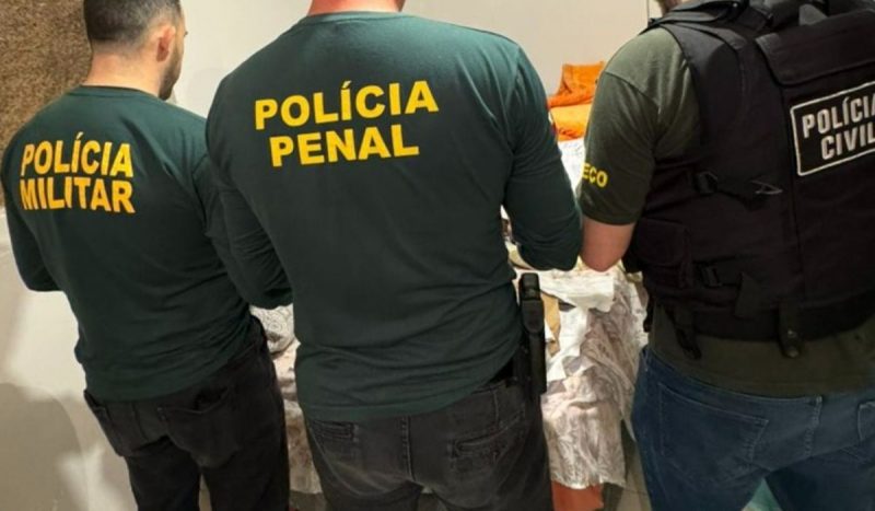 foto mostra policiais militares, penais e civis de costas, na operação com quatro prefeitos presos