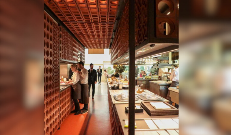 Foto mostra restaurante com paredes em tons terrosos e garçons ao lado esquerdo. Imagem é usada para ilustrar matéria sobre o melhor restaurante do mundo