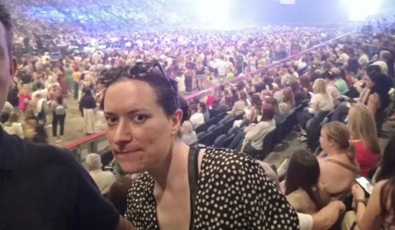 Mulher branca com expressão séria posando em frente à multidão em show