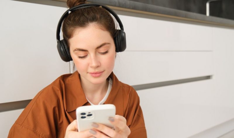 Mulher de fone ouvido mexendo no celular para atrair fama