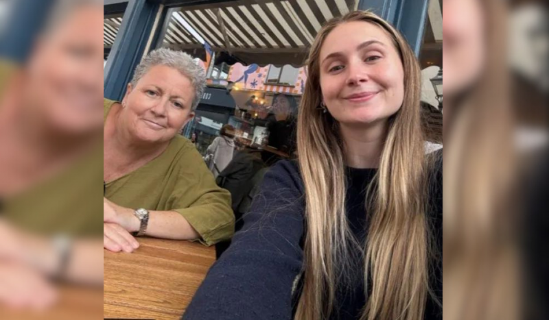 Mulher de cabelos grisalhos à esquerda e jovem loira de cabelos compridos e loiros sorrindo sem mostrar os dentes 