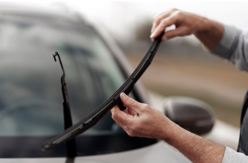 na foto aparece um para-brisas quebrado sendo mostrado pelo dono do carro