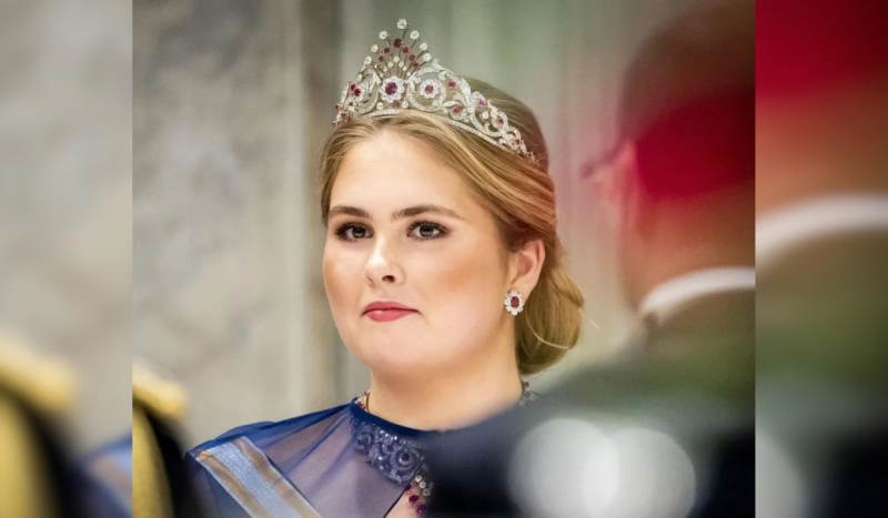 Foto mostra a princesa herdeira da Holanda Catharina-Amalia, mulher branca e loira usando uma coroa cravejada de pedras preciosas olhando para o horizonte enquanto é fotografada em evento público
