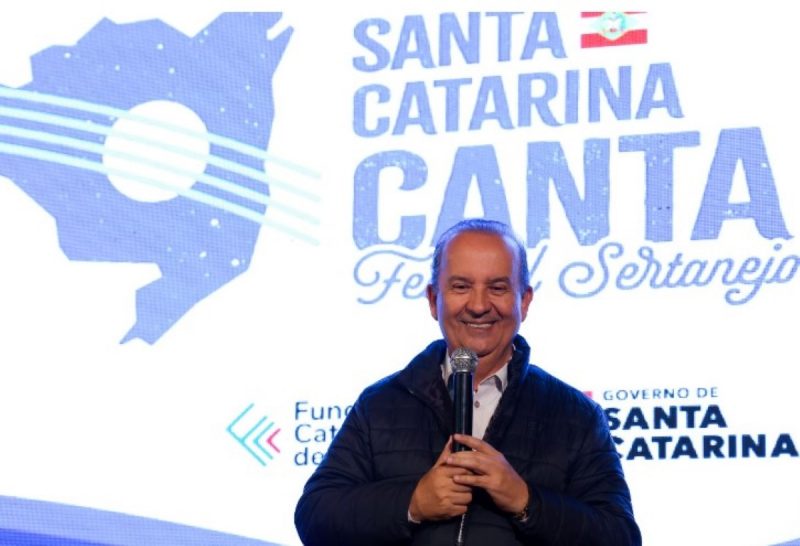 na foto aparece o governador Jorginho Mello sorrindo no lançamento do projeto Santa Catarina Canta