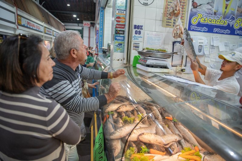 Foto mostra pessoas comprando tainha no mercado público de Florianópolis 