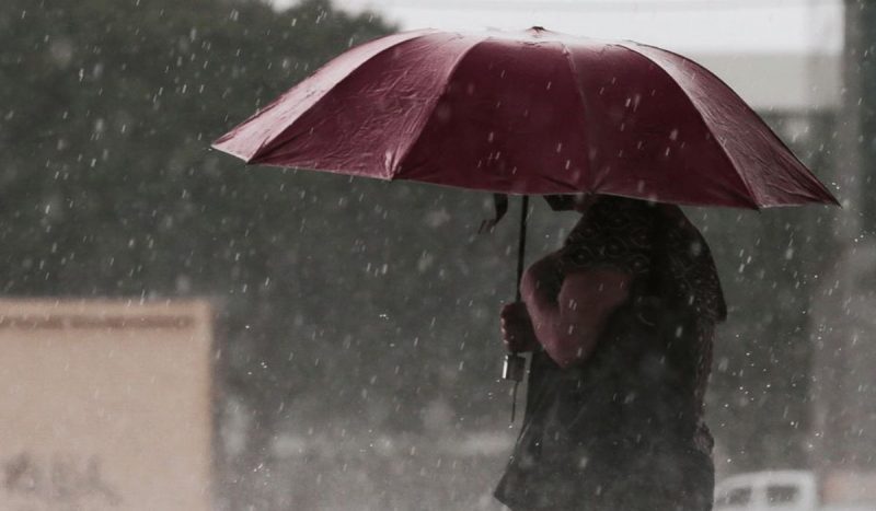 alerta para tempestades indica rajadas de até 100 km/h no Sul do Brasil, foto de mulher com guarda-chuva no meio da chuva