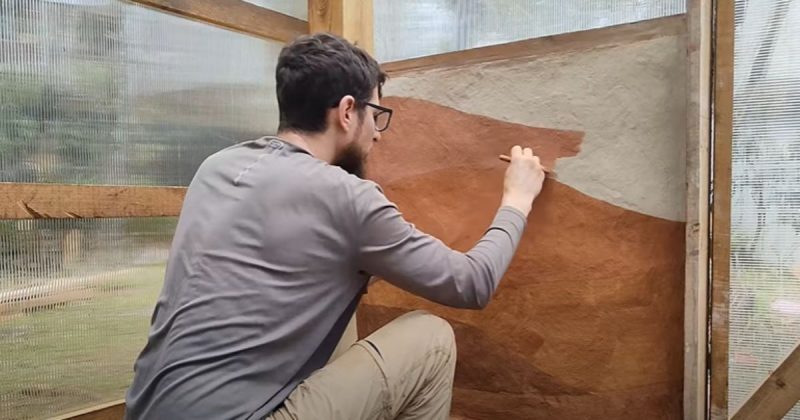 Homem pintando a parede com tinta de terra