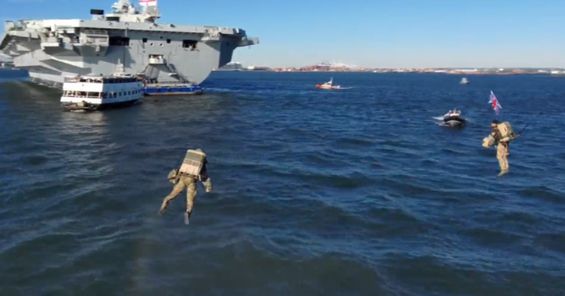 Homens voado sobre o mar, com barco e navio de guerra atrás