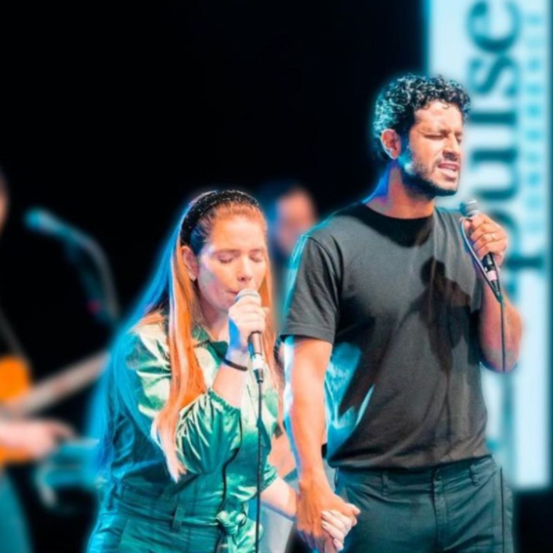 Cantora gospel Camila Campos em palco com microfone na mão ao lado do marido, Leo Zagueiro