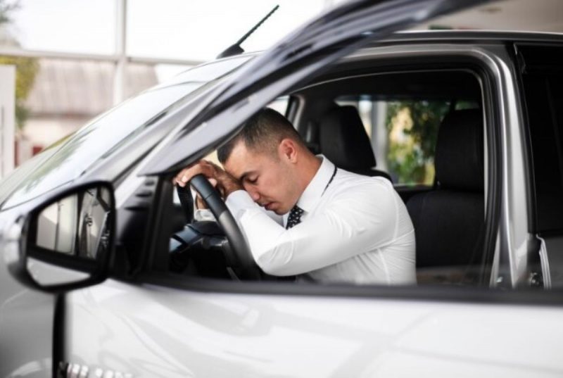 na foto motorista aparece dormindo no carro por estar cansado