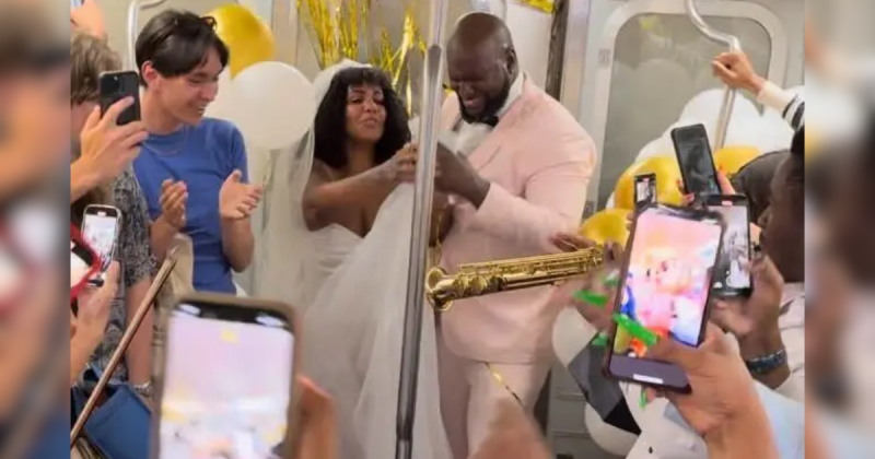 Casal vestido de branco, com roupas de noivo, durante casamento que foi realizado dentro de metrô