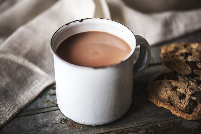 Xícara de chocolate quente em cima de mesa com biscoitos 