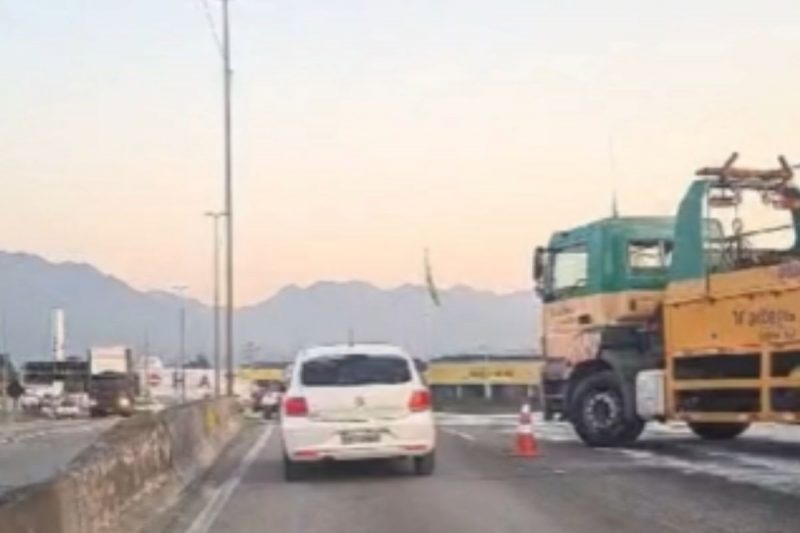 Caminhão com problemas mecânicos parado na rodovia e um carro branco passando ao lado