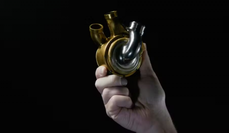 Mão de pessoa branca segurando pela mecânica nas cores prata e dourado simulando um coração humano