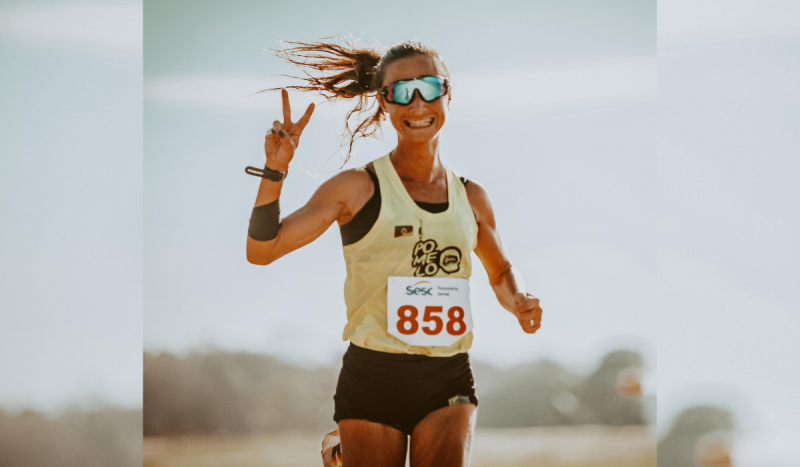 Atleta Luisa Giampaoli do RS que morreu de leptospirose - mulher bronzeada aparece correndo e sorrindo usando regata amarela e ficha com o número dela de corrida