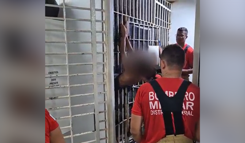 Frame de vídeo mostra agentes dos bombeiros tentando retirar homem preso entre grades de cela 