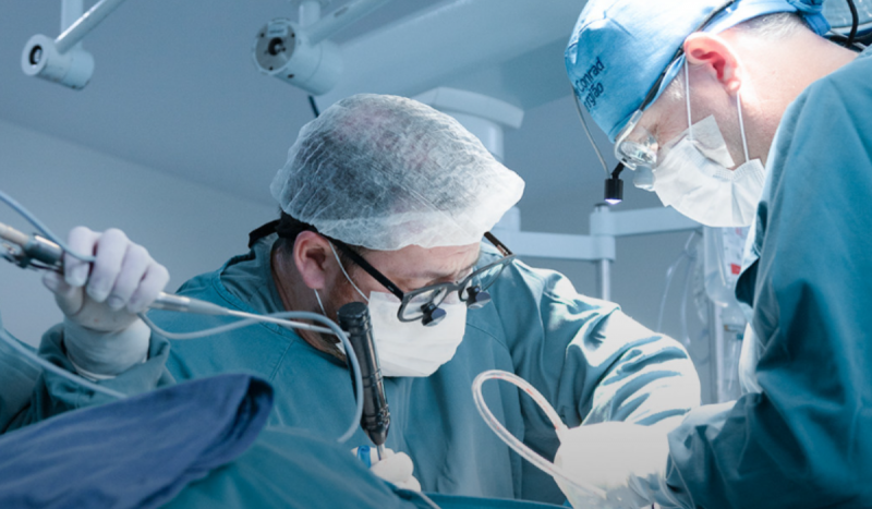 Neurocirurgião Wuiker Knoner, que trata a pior dor do mundo em SC - médicos com roupas cirúrgicas azuis operando paciente