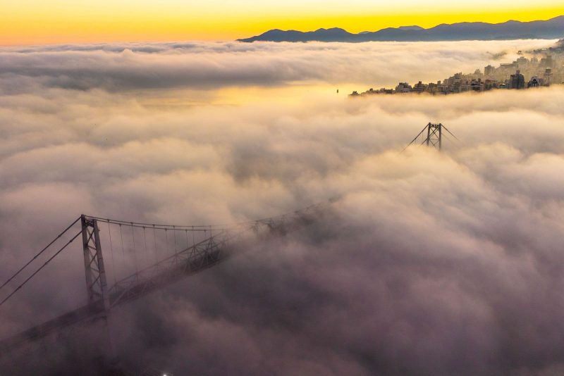 foto mostra nevoeiro encobrir ponte Hercílio Luz, em Florianópolis, no amanhecer