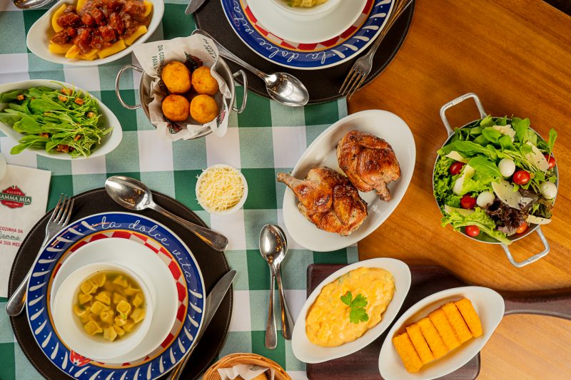 mesa com pratos típicos italianos, como massas, frango grelhado, polenta